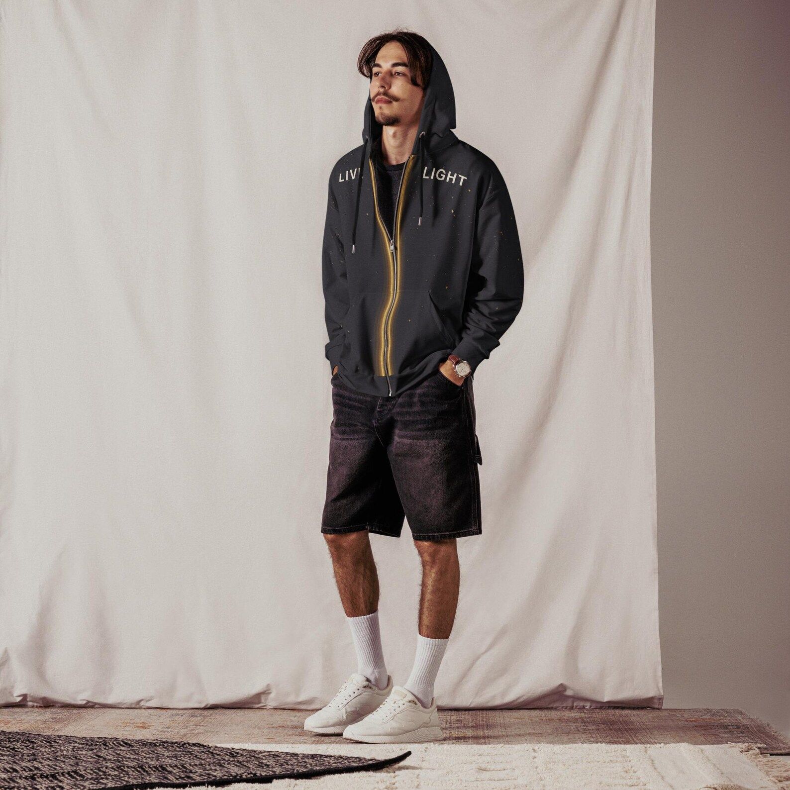 Model standing in the Live Light hoodie with the hood raised and the celestial front design visible